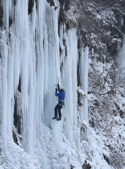 Alpinista wspina się po lodospadzie w Rudawce Rymanowskiej