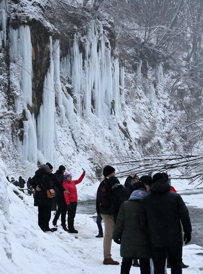 Ludzie robią sobie zdjęcia przy wielkich soplach lodu w Rudawce Rymanowskiej