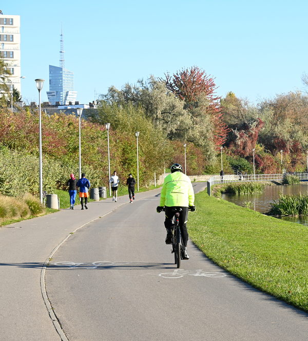 Rowerzysta na ścieżce rowerowej nad rzeką w Rzeszowie, w tle panorama miasta